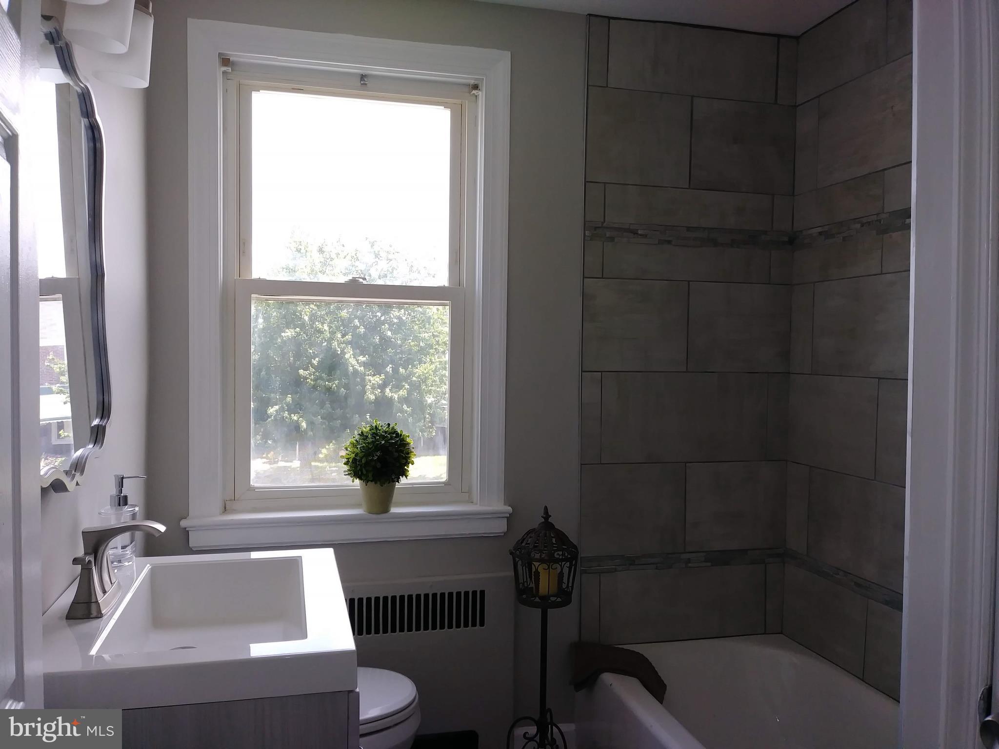 3812 Ednor Road Baltimore, MD 21218 - Photo 12 of 22 a bathroom with a tub a sink and a window