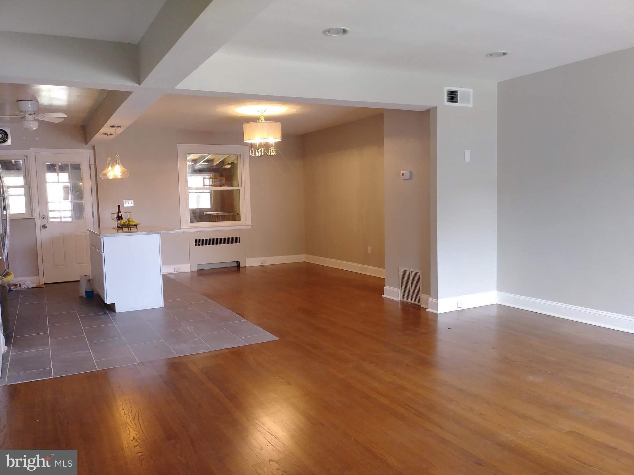 3812 Ednor Road Baltimore, MD 21218 - Photo 7 of 22 a view of an empty room with wooden floor and a kitchen