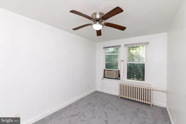 an empty room with windows and ceiling fan
