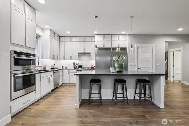 a kitchen with granite countertop a wooden floor and white stainless steel appliances