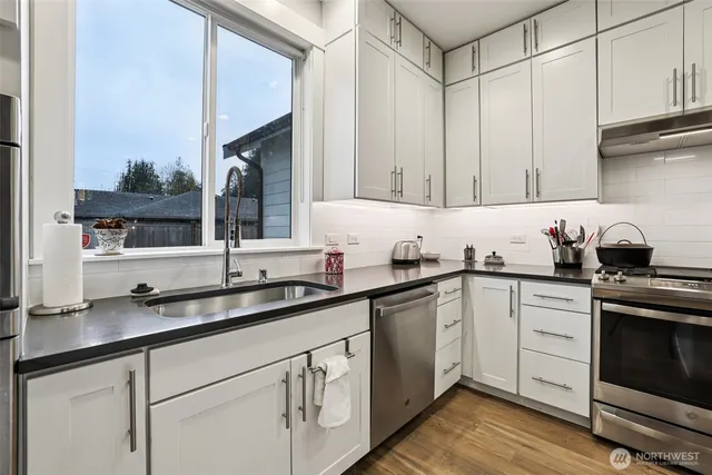 a kitchen with granite countertop a sink cabinets and stainless steel appliances