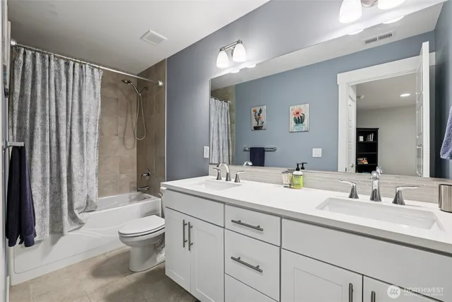 a bathroom with a double vanity sink toilet mirror and bathtub