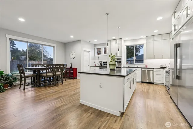 a kitchen with stainless steel appliances kitchen island granite countertop wooden floors and white cabinets