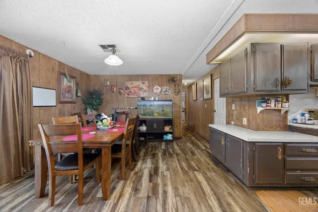 a kitchen with stainless steel appliances kitchen island granite countertop a dining table chairs and a refrigerator
