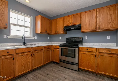 a kitchen with granite countertop wooden cabinets and a stove top oven