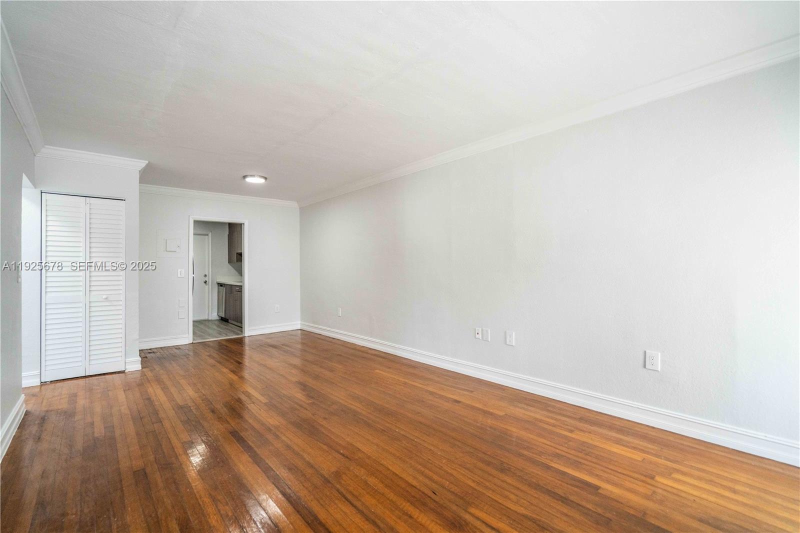 7925 Hawthorne Avenue, Unit 1 Miami Beach, FL 33141 - Photo 5 of 20 a view of an empty room with wooden floor and kitchen