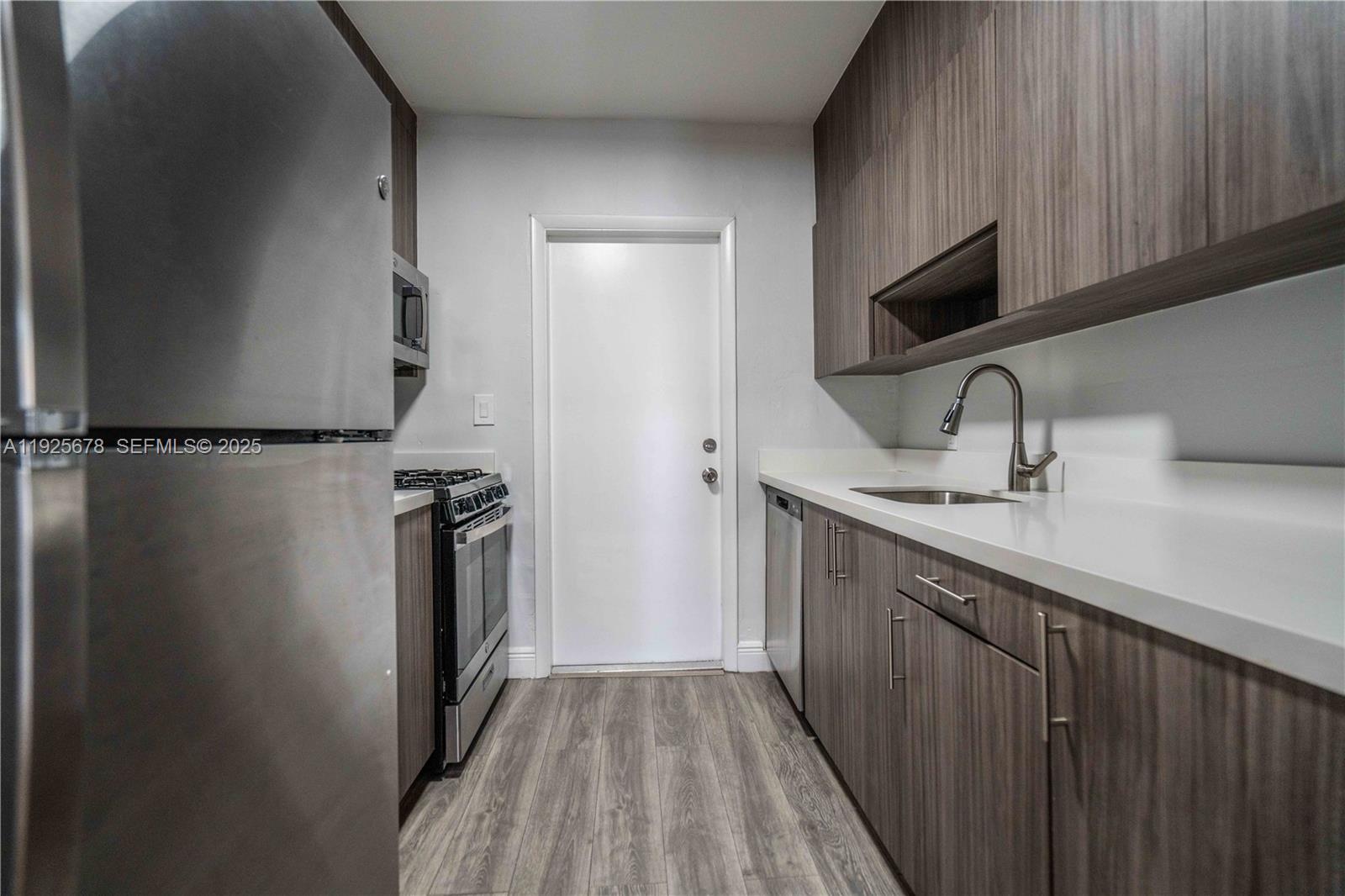 7925 Hawthorne Avenue, Unit 1 Miami Beach, FL 33141 - Photo 8 of 20 a kitchen with a sink a refrigerator and cabinets