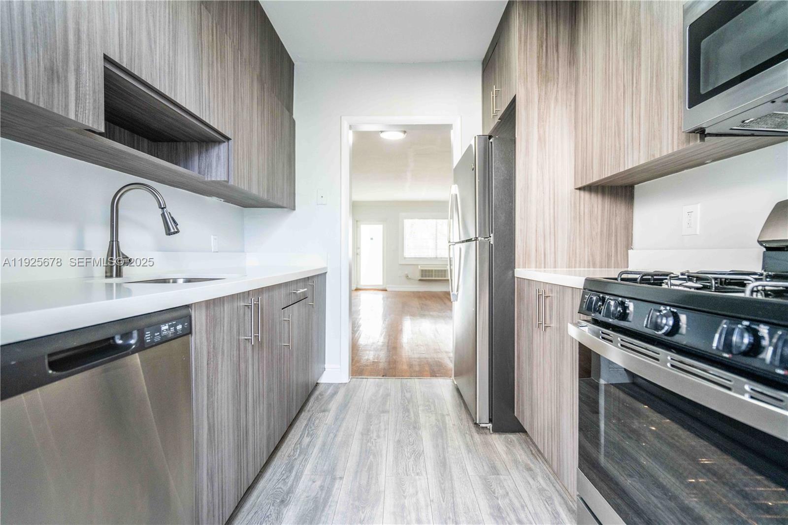 7925 Hawthorne Avenue, Unit 1 Miami Beach, FL 33141 - Photo 9 of 20 a kitchen with stainless steel appliances a sink dishwasher a stove and a microwave oven with wooden floor