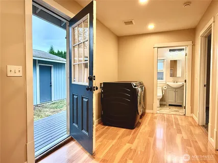 a view of a hallway with wooden floor and a bathroom