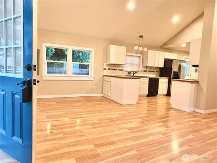 a kitchen with stainless steel appliances kitchen island granite countertop a refrigerator a stove top oven and a sink with granite countertops