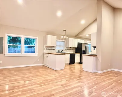 a view of kitchen with stainless steel appliances kitchen island wooden cabinets and window
