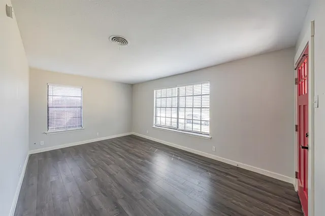 a view of an empty room with wooden floor and windows