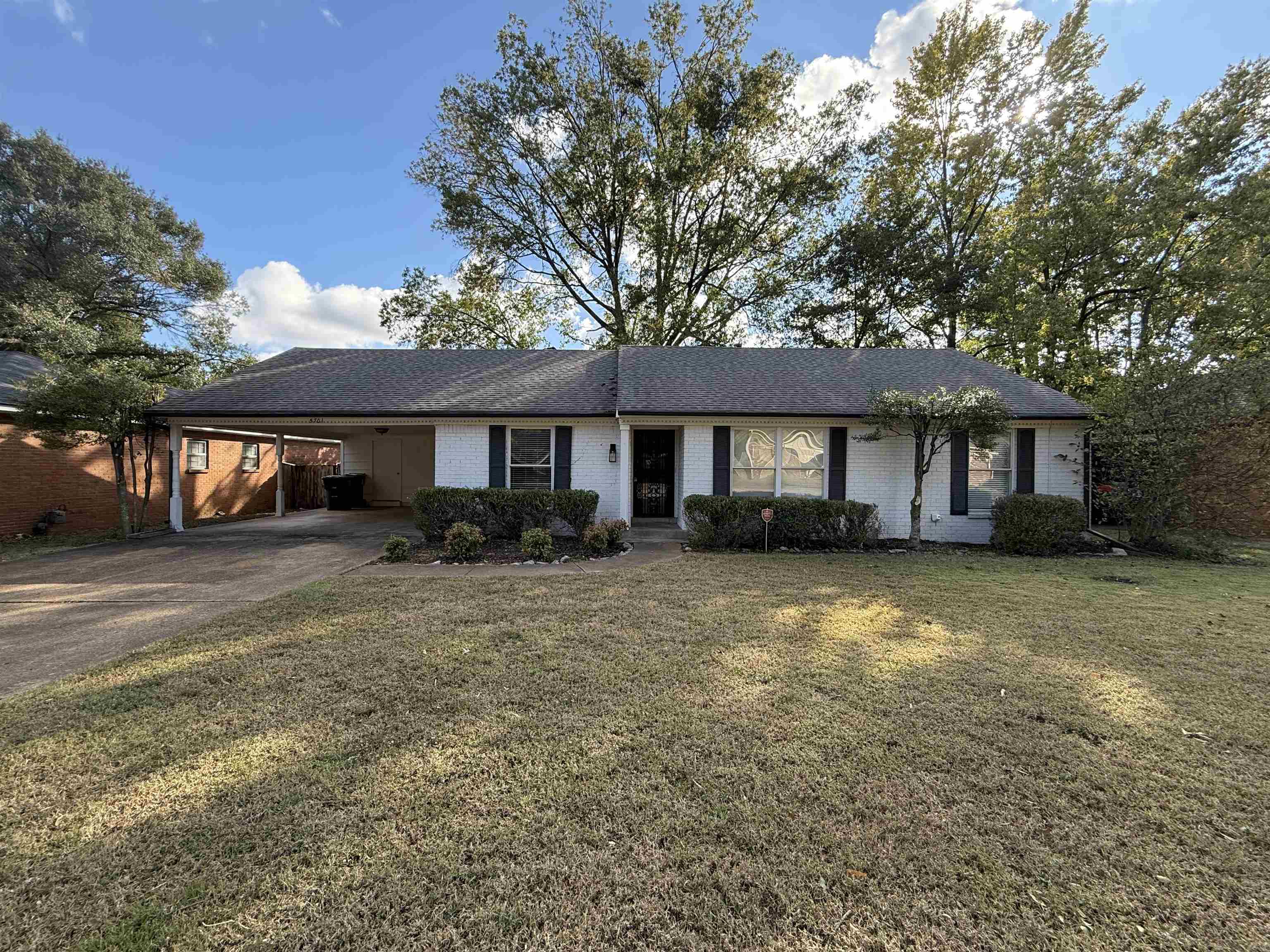 Ranch-style house featuring a front yard, a carport, brick siding, and driveway