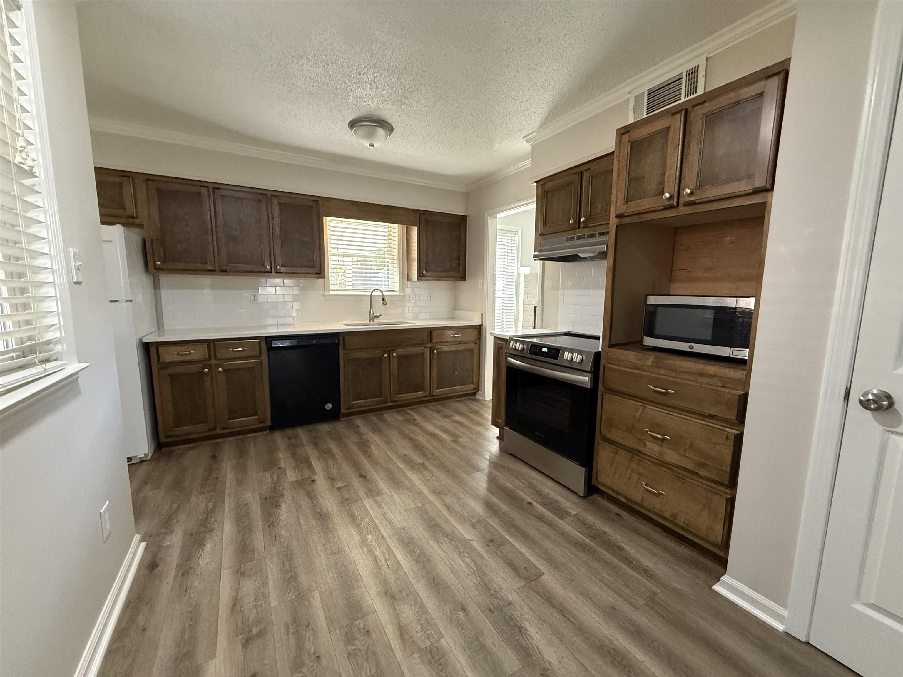 5701 Baird Drive Memphis, TN 38119 - Photo 3 of 12 Kitchen with crown molding, dark brown cabinets, dark wood finished floors, backsplash, and a textured ceiling