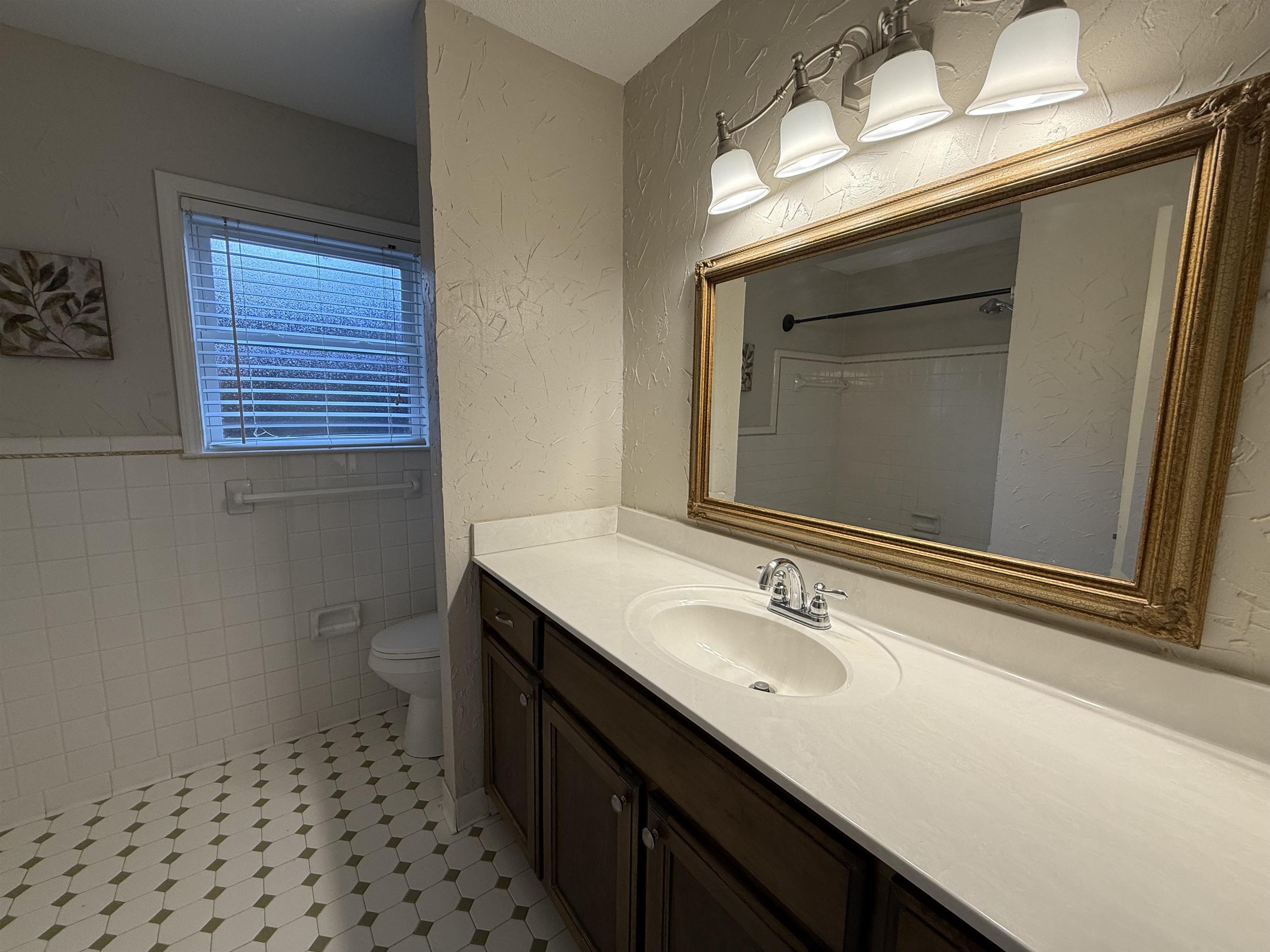 5701 Baird Drive Memphis, TN 38119 - Photo 5 of 12 Full bath featuring a textured wall, vanity, tile walls, a shower, and a wainscoted wall