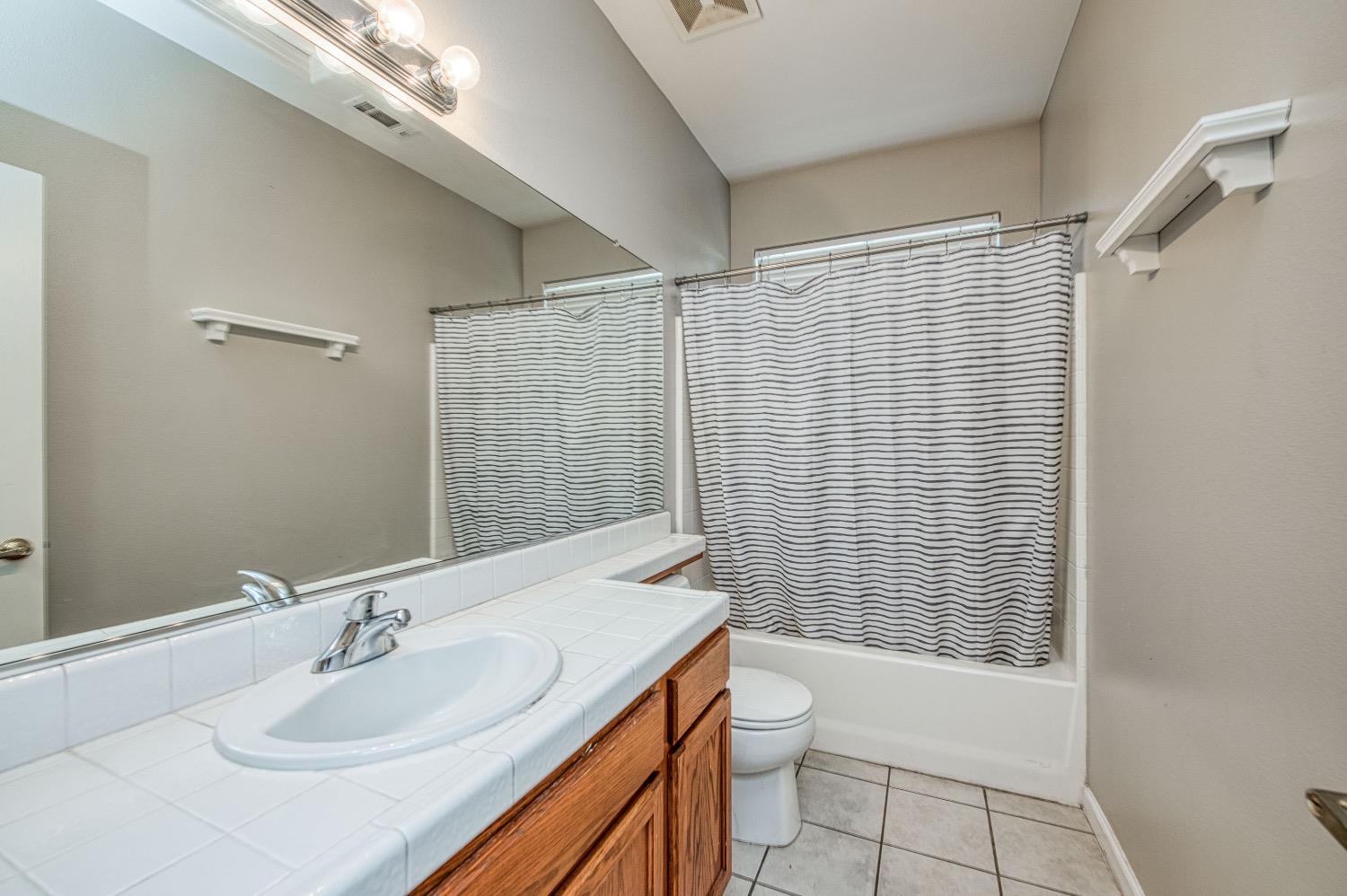1648 North Avignon Lane Clovis, CA 93619 - Photo 16 of 27 a bathroom with a sink toilet and shower