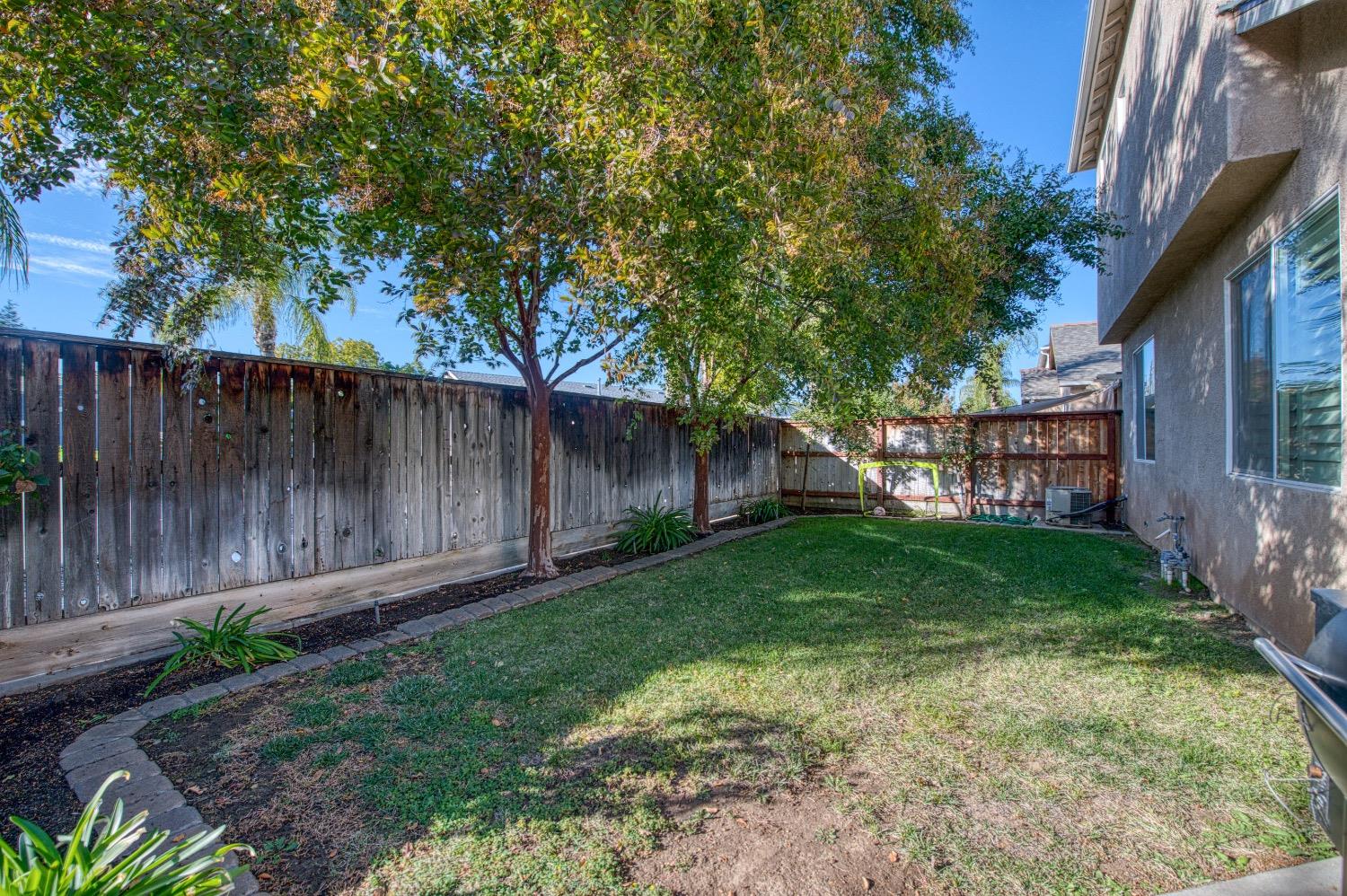 1648 North Avignon Lane Clovis, CA 93619 - Photo 26 of 27 a view of backyard with wooden fence and a large tree