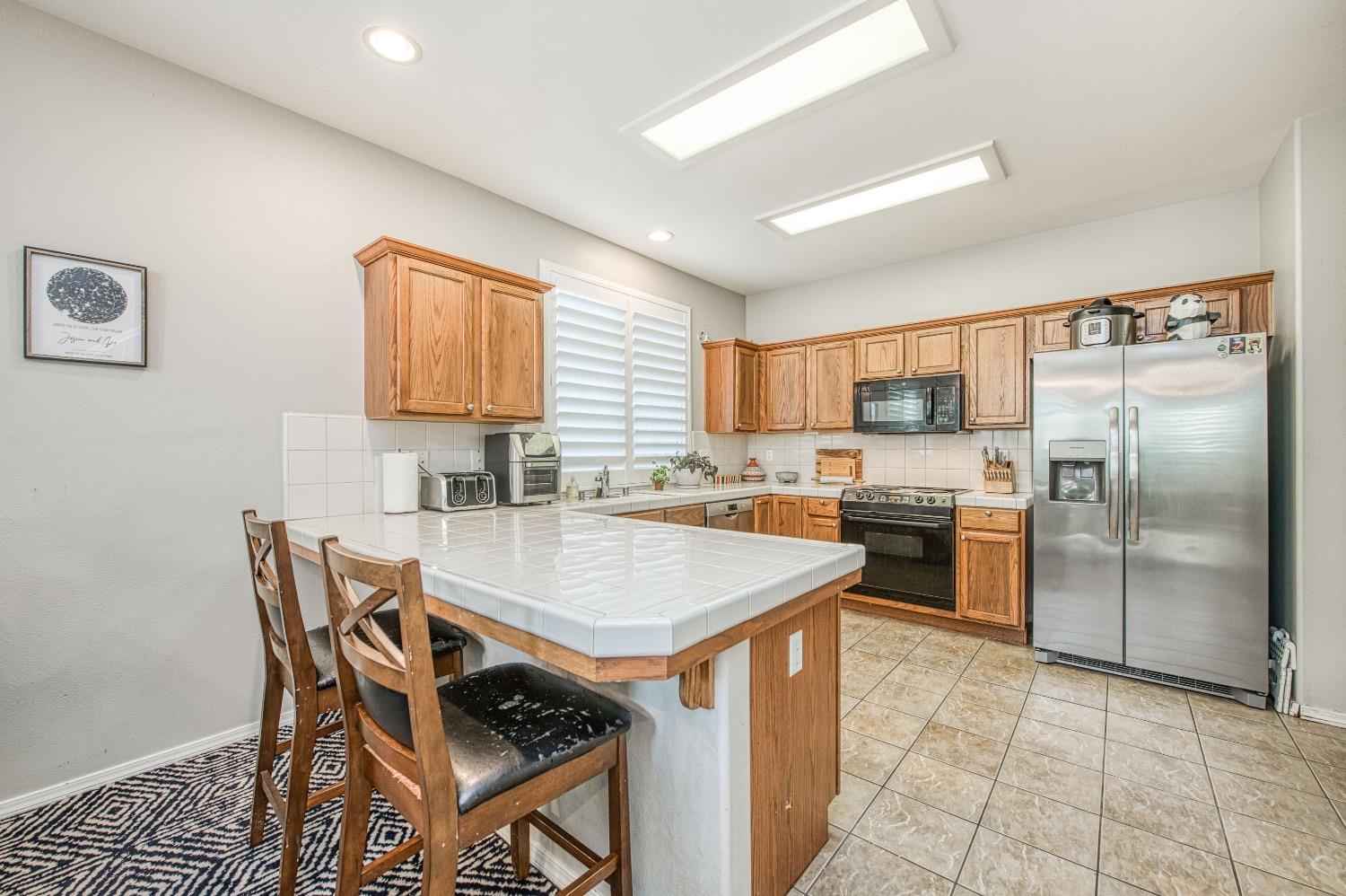 1648 North Avignon Lane Clovis, CA 93619 - Photo 10 of 27 a kitchen with a refrigerator a stove a sink a dining table and chairs