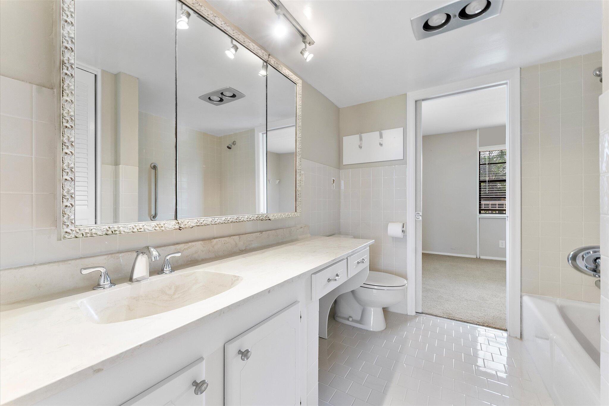 501 Southwest 11th Place, Unit 418 Boca Raton, FL 33432 - Photo 20 of 35 a bathroom with a sink a toilet and a large mirror
