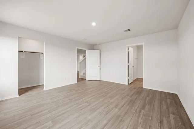 a view of an empty room with wooden floor and closet