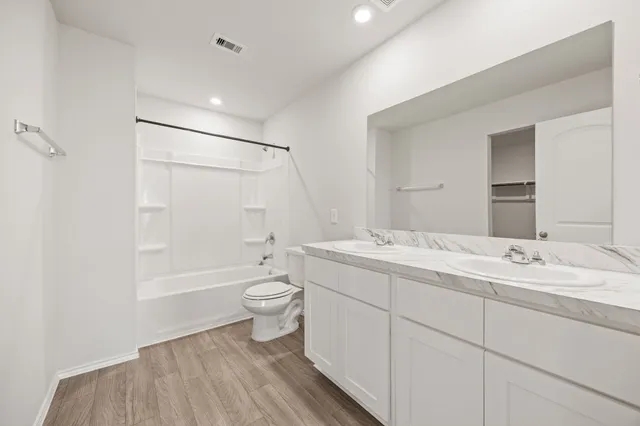 a bathroom with a double vanity sink toilet mirror and bathtub