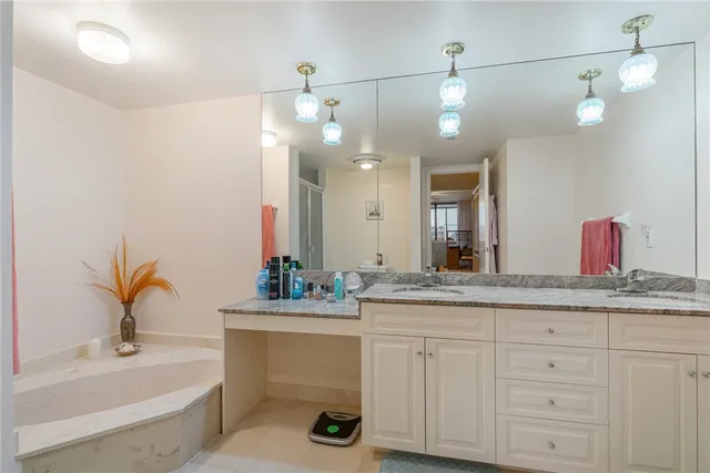 a bathroom with a sink double vanity granite and a bathtub