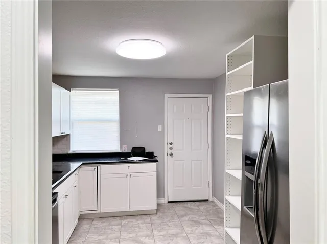 a kitchen with a refrigerator and white cabinets