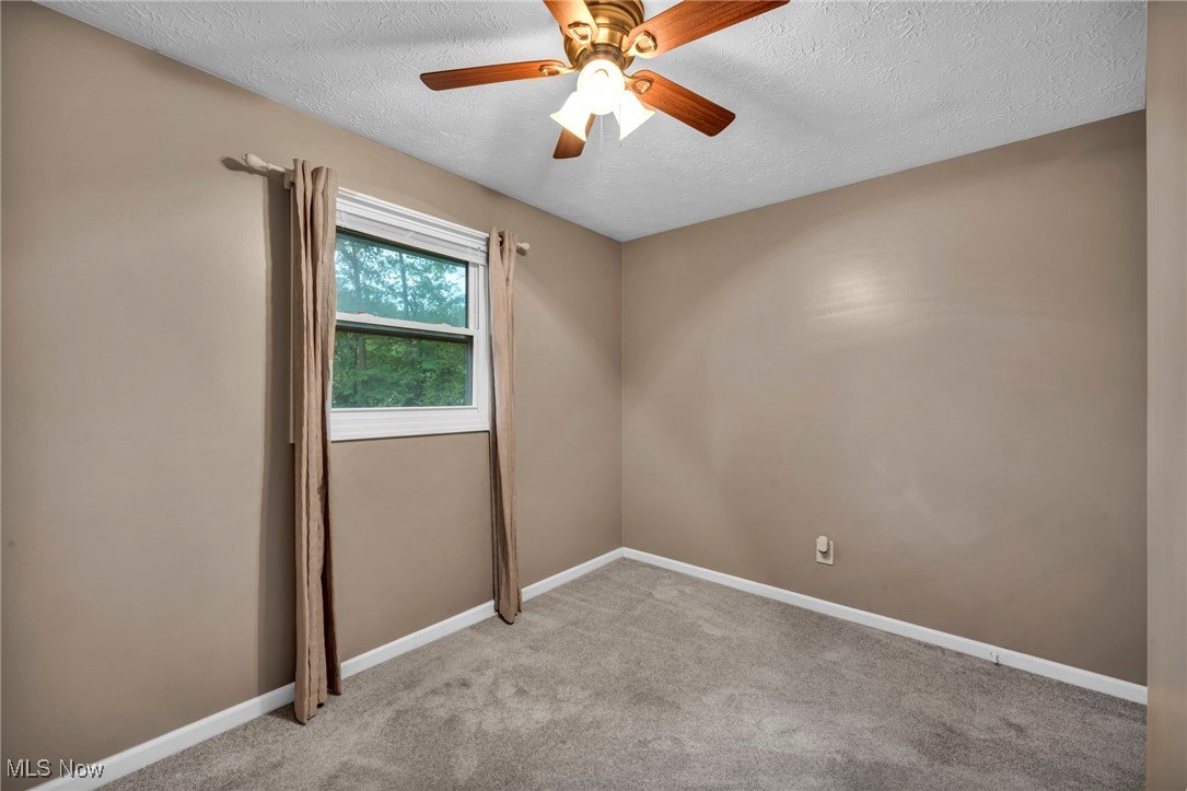 47655 Cooper Foster Park Road Amherst, OH 44001 - Photo 18 of 49 Spare room featuring a textured ceiling, light colored carpet, and a ceiling fan