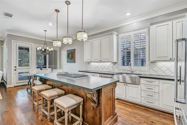a kitchen with granite countertop a sink a center island a stove and a wooden floor