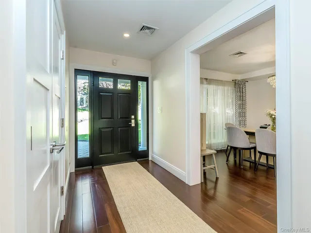 a view of a hallway with wooden floor table and chairs