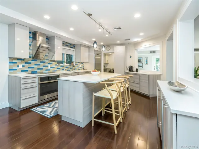 a kitchen with stainless steel appliances a stove a sink dishwasher and white cabinets with wooden floor