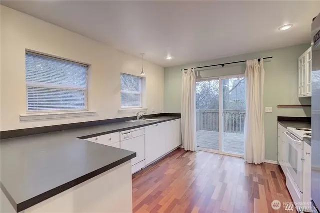 a kitchen with stainless steel appliances granite countertop a stove a sink and a refrigerator with wooden floor