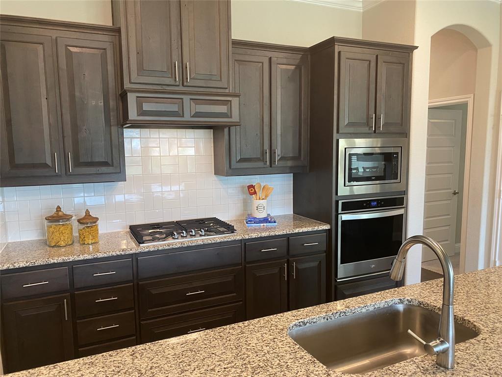 209 Johnson Street Granbury, TX 76048 - Photo 8 of 40 Kitchen with sink, tasteful backsplash, stainless steel appliances, and light stone counters
