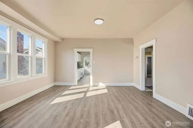 a view of an empty room with wooden floor and a window