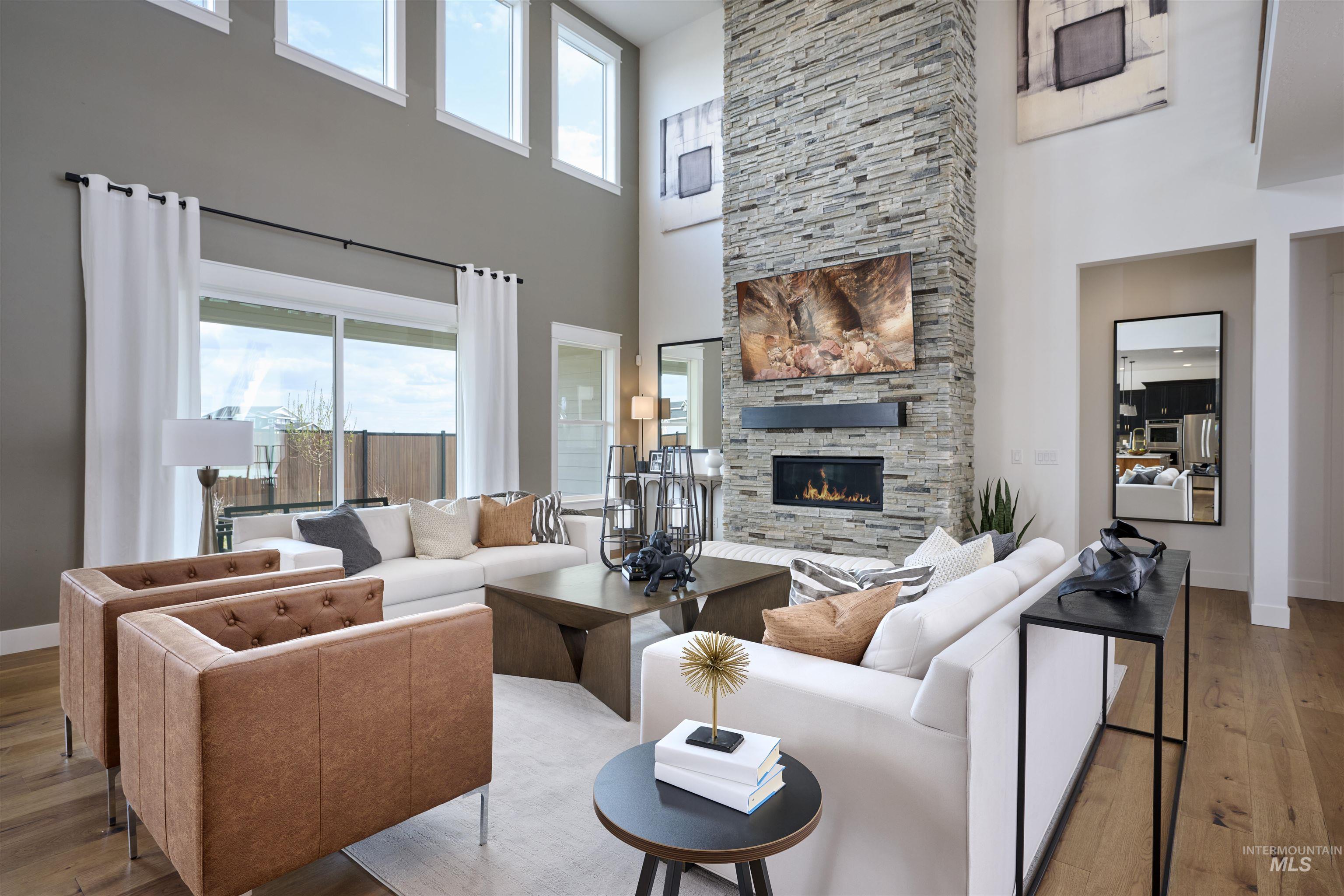 Living room featuring wood-type flooring, a high ceiling, and a stone fireplace