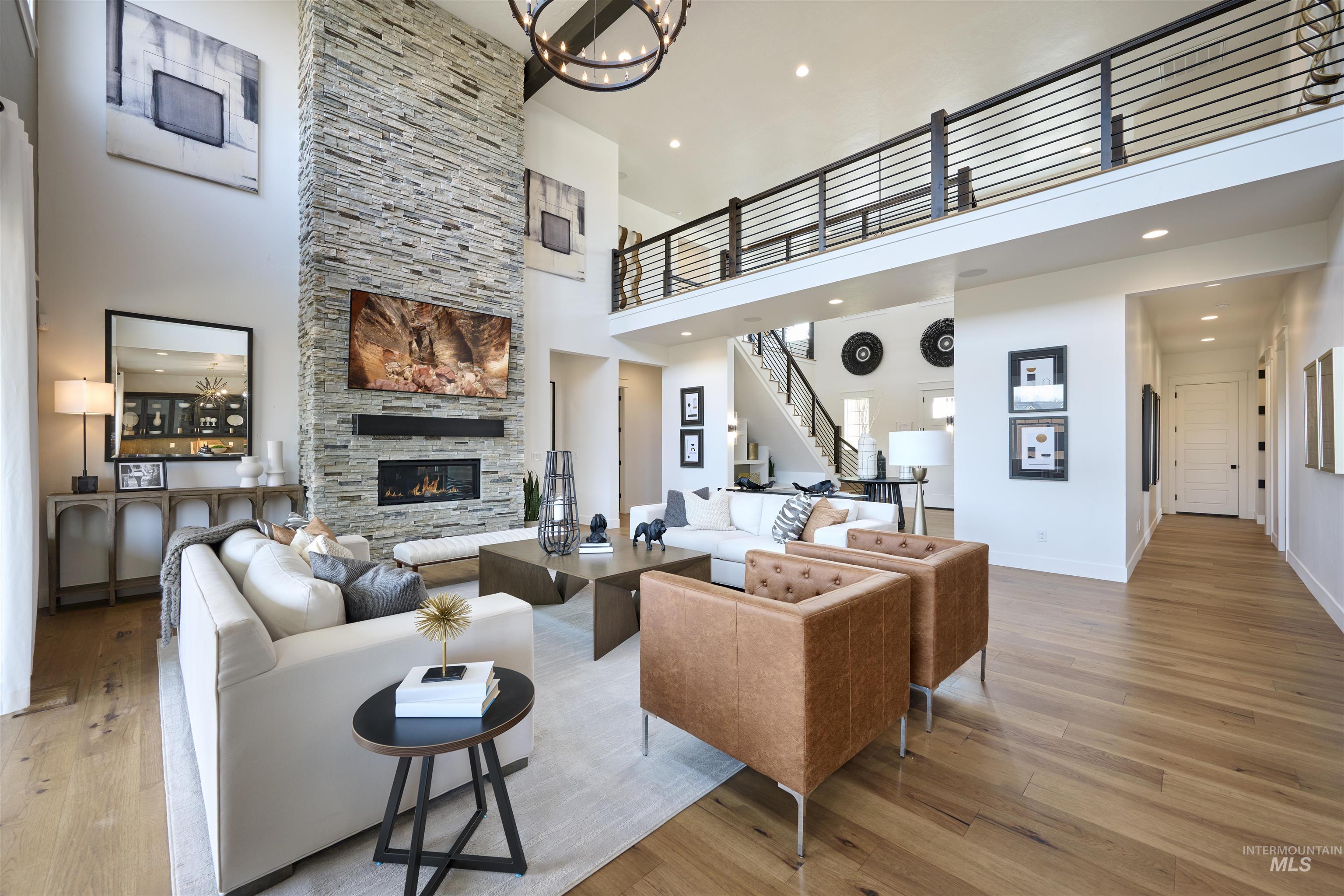 3370 North Del Sol Way Star, ID 83669 - Photo 5 of 30 Living room with a high ceiling, a stone fireplace, light wood-style flooring, and hanging lights