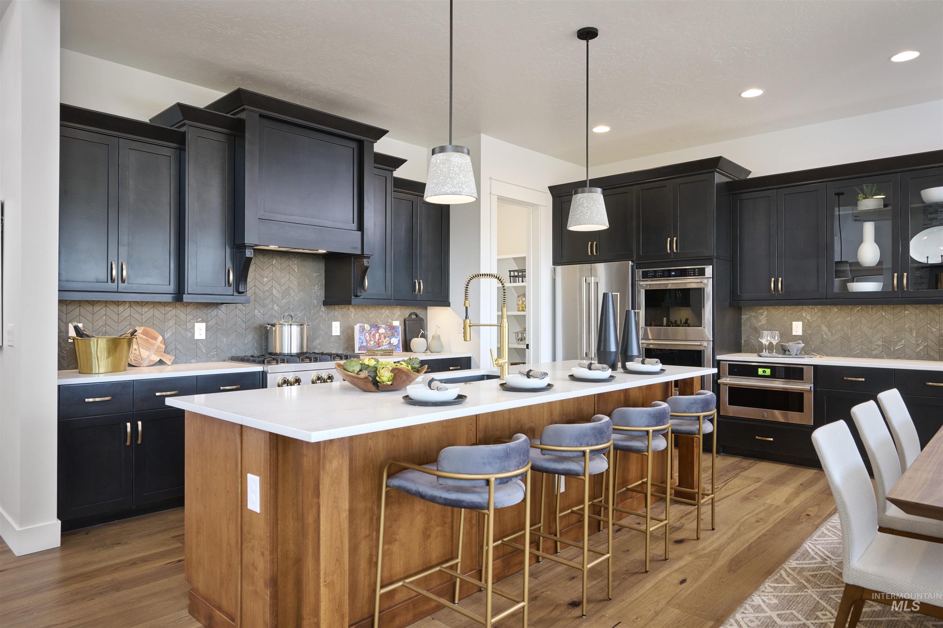 3370 North Del Sol Way Star, ID 83669 - Photo 7 of 30 Kitchen featuring dark cabinets, glass fronted cabinets, stainless steel appliances, decorative light fixtures, and a kitchen bar