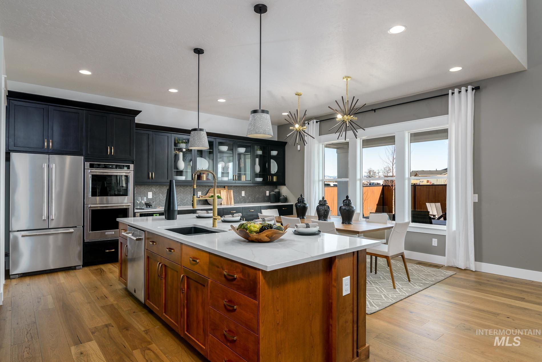 3370 North Del Sol Way Star, ID 83669 - Photo 8 of 30 Kitchen featuring glass fronted cabinets, stainless steel appliances, light wood-style flooring, and hanging light fixtures