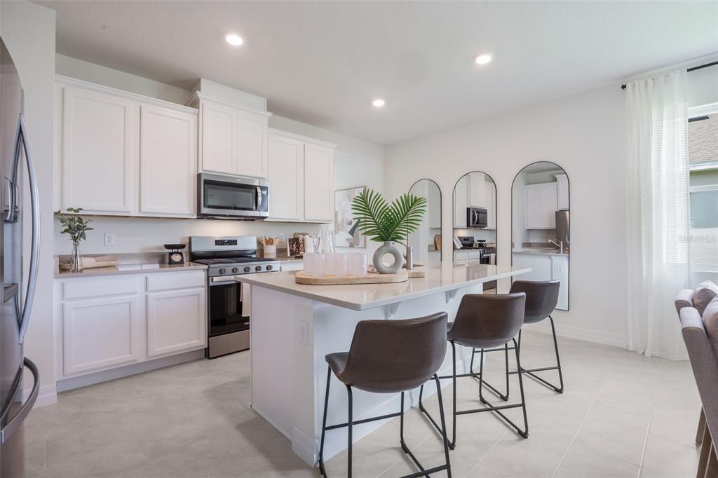 3973 Kennebunk Loop Mount Dora, FL 32757 - Photo 11 of 37 a kitchen with stainless steel appliances granite countertop a stove a sink a refrigerator and a microwave
