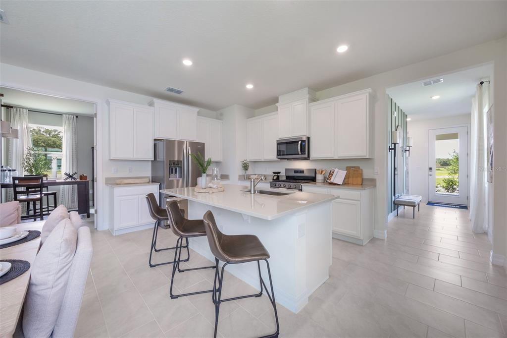 3973 Kennebunk Loop Mount Dora, FL 32757 - Photo 7 of 37 a kitchen with a dining table chairs refrigerator and cabinets