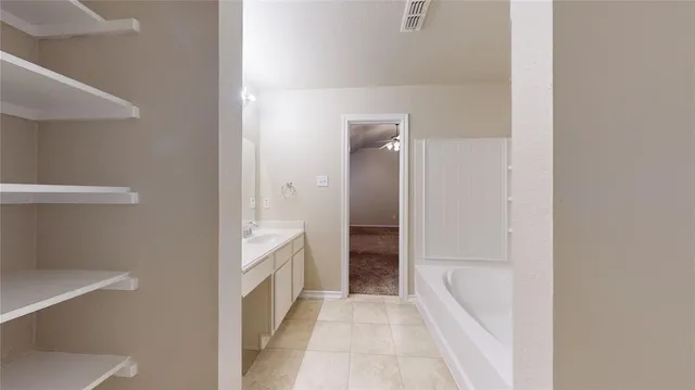 an empty room with chandelier fan and windows