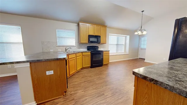 a kitchen with granite countertop a sink cabinets and wooden floor