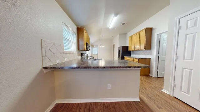 a kitchen with stainless steel appliances granite countertop a sink a stove and a wooden floor