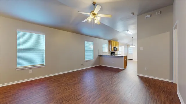 a view of an empty room with window and wooden floor