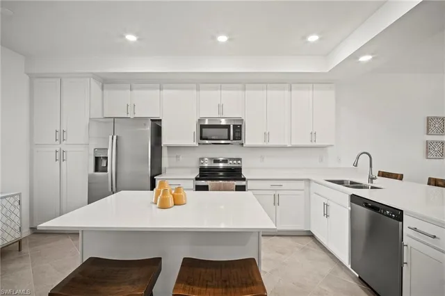 a kitchen with a sink a stove a refrigerator and white cabinets