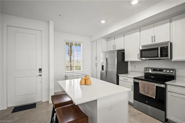 a kitchen with a refrigerator a stove a microwave and island with wooden floor