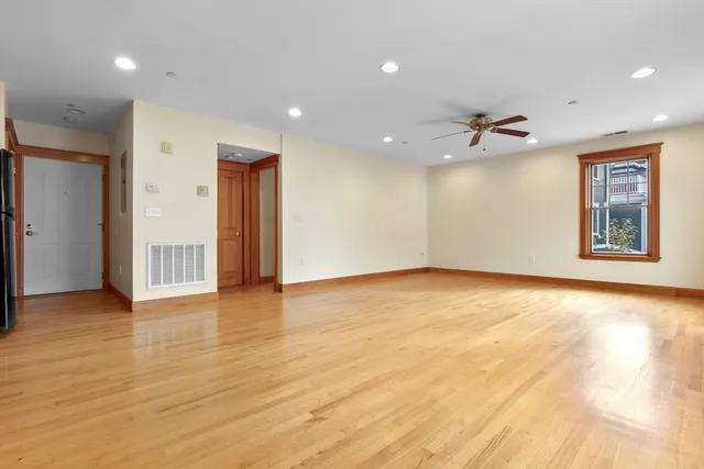 a view of an empty room with window and wooden floor