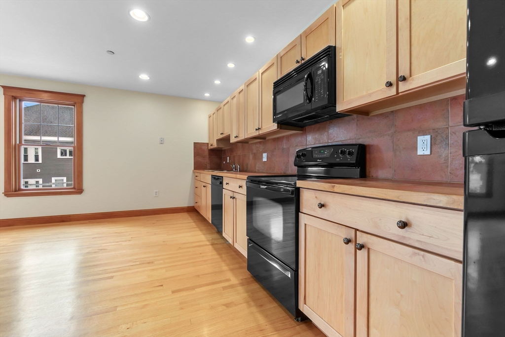 50 Maple Street, Unit 5 Danvers, MA 01923 - Photo 5 of 21 a kitchen with stainless steel appliances granite countertop a stove a sink and a microwave