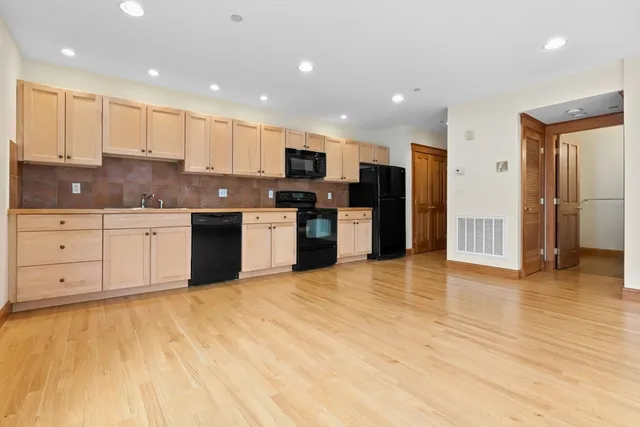 a large kitchen with stainless steel appliances granite countertop a stove a sink and a refrigerator