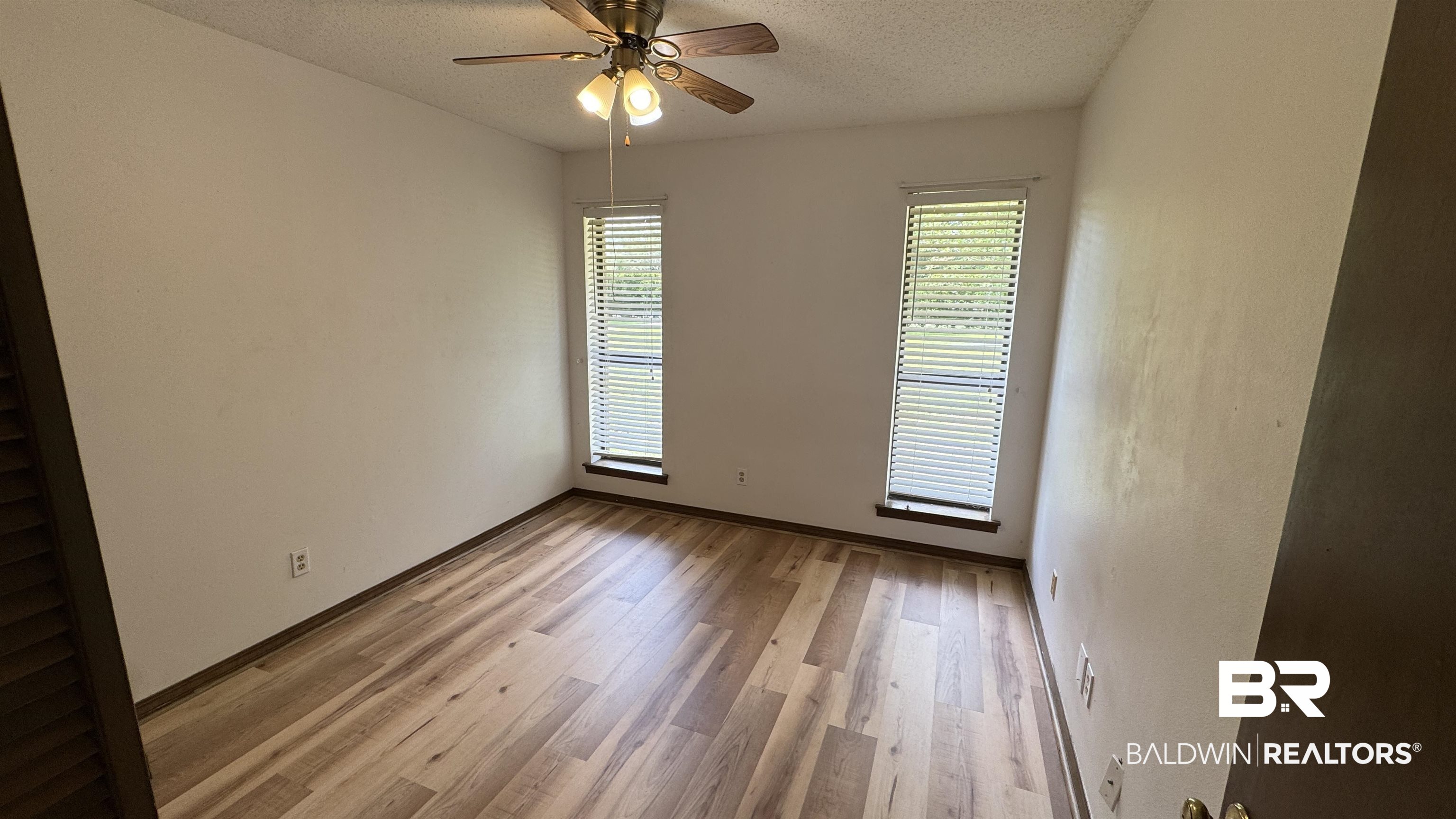33370 Highway 98 Lillian, AL 36549 - Photo 32 of 58 Room featuring wood-finish flooring, two vertical windows with blinds, and a ceiling fan with integrated lighting